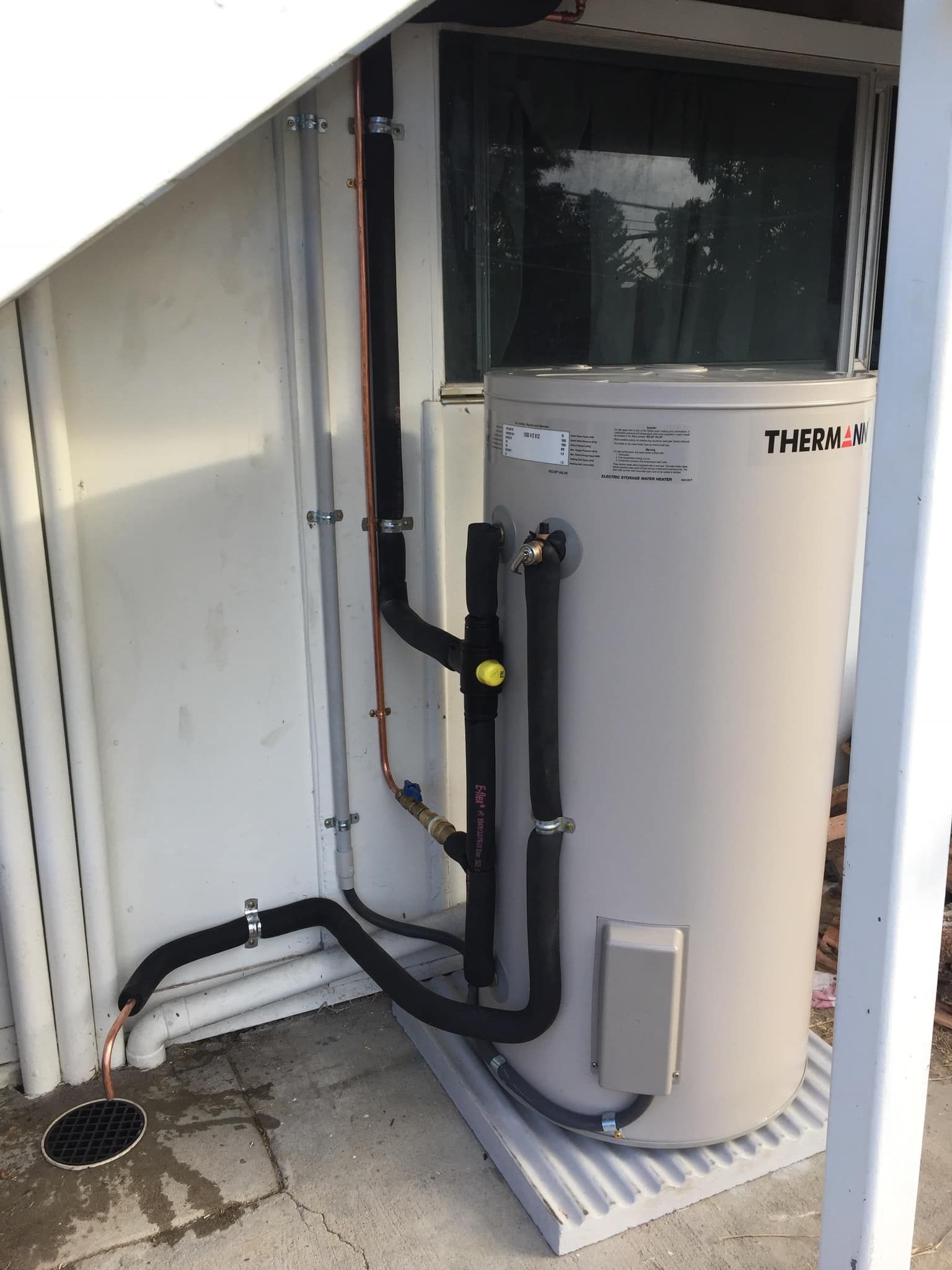 A Beige Rheem Water Heater Installed Outdoors — Hales Plumbing & Roofing In The Range, QLD