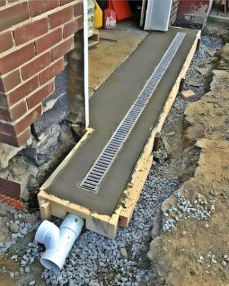 Concrete Trench Drain With Metal Grate Installed Next to a Brick Wall — Hales Plumbing & Roofing In The Range, QLD