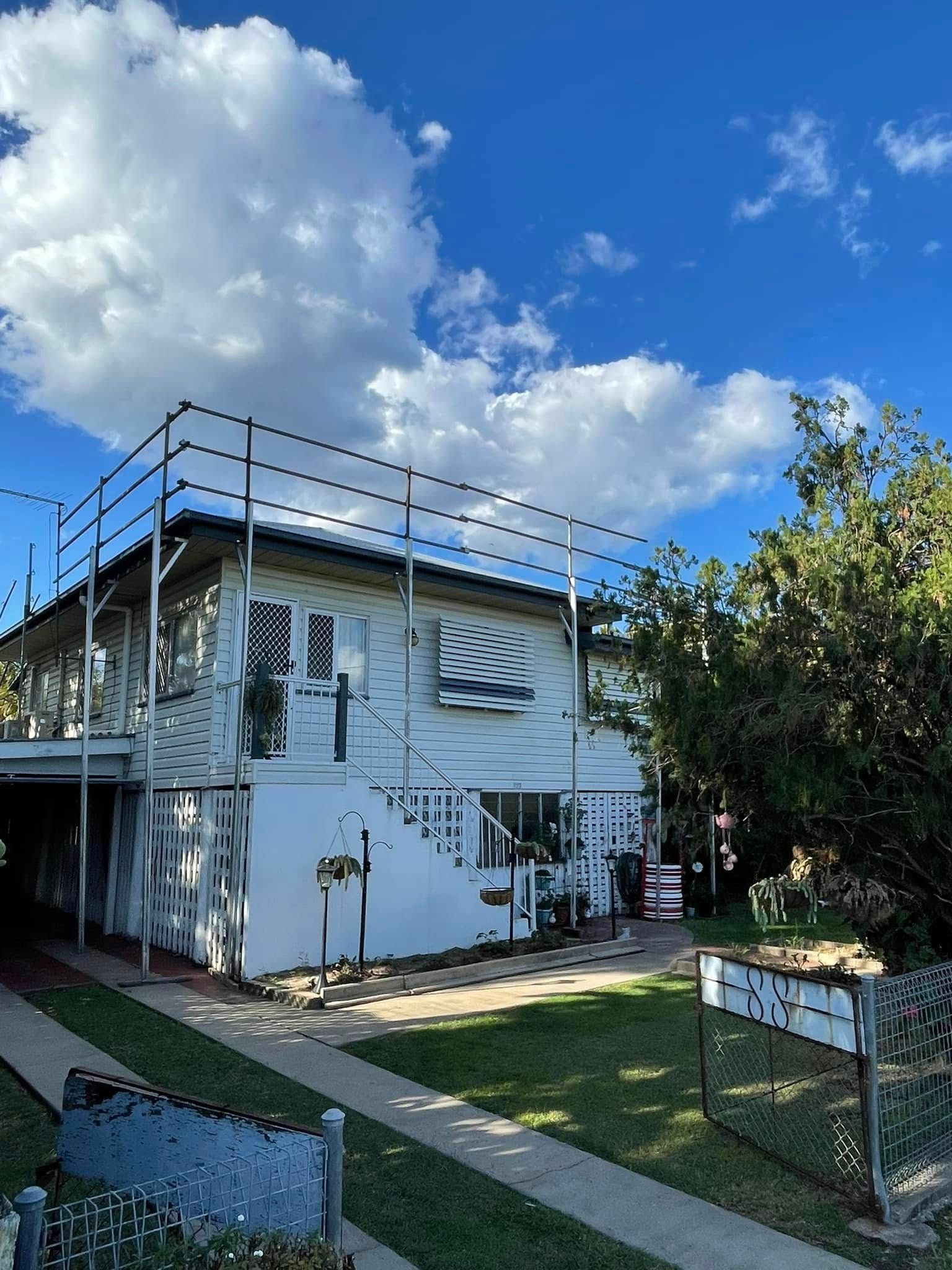 Person in White Gloves Caulking a Metal Roof Near Brown Roof Tiles — Hales Plumbing & Roofing In The Range, QLD