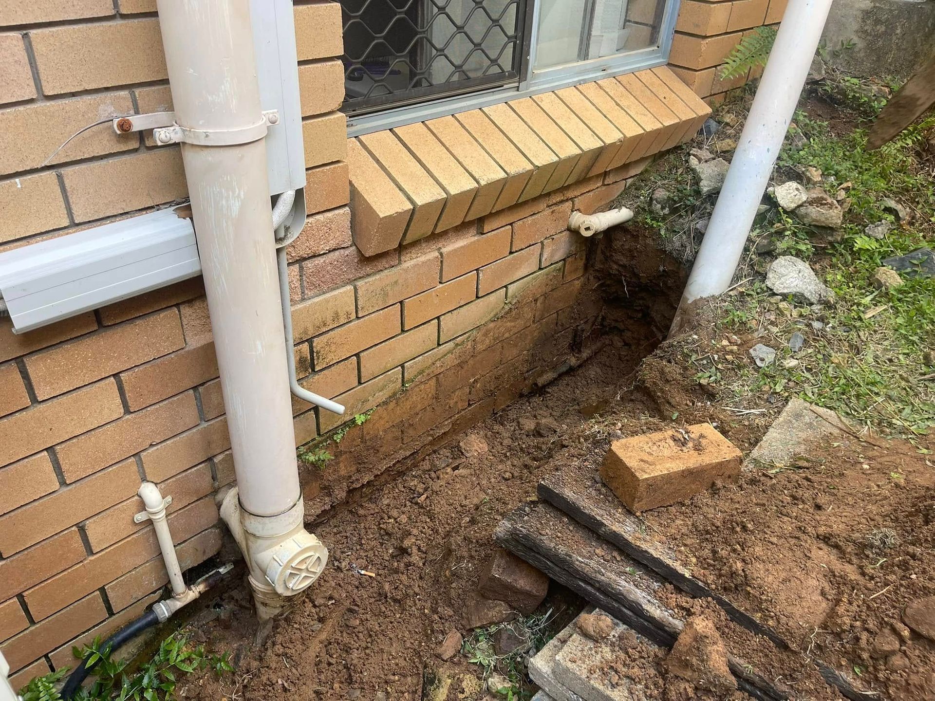 Man Using a Drain Snake to Unclog a Pipe Outside — Hales Plumbing & Roofing In The Range, QLD