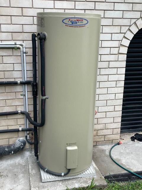 Tan Australian Rheem Hot Water Tank Mounted Against a Brick Wall — Hales Plumbing & Roofing In The Range, QLD