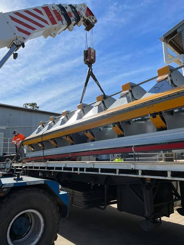 A Crane Is Lifting A Large Piece Of Metal On Top Of A Truck — Commercial Roofs in Toowoomba, QLD