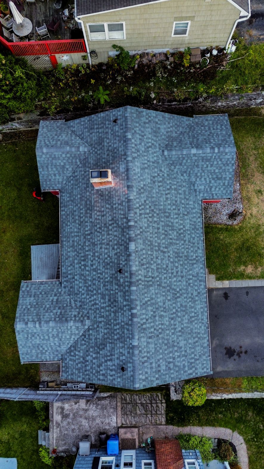 Aerial view of a blue-roofed house with a driveway and neighboring homes.