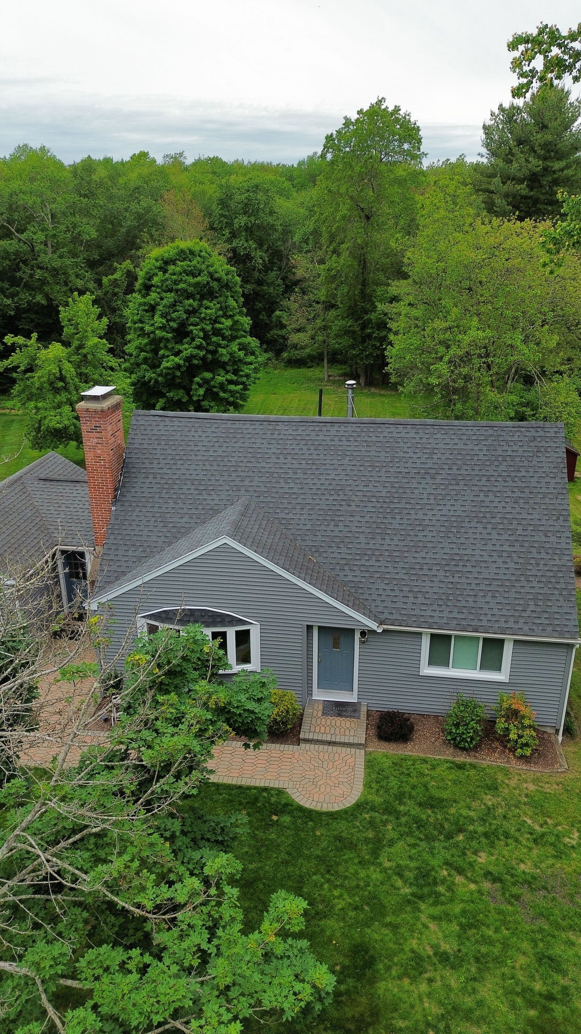 An aerial view of a white house with blue shutters and a gray roof.
