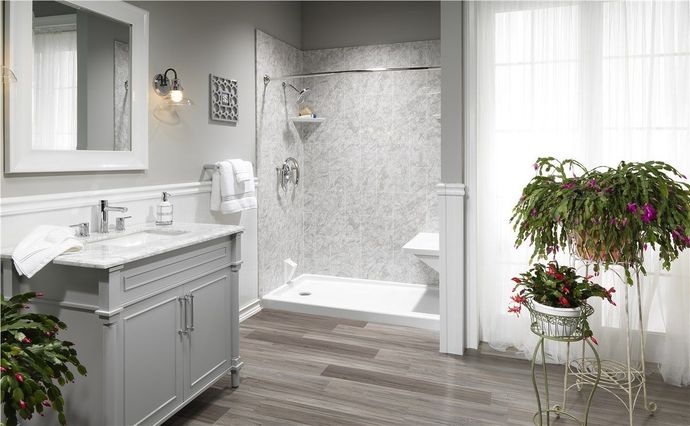 Bathroom with a gray vanity, walk-in shower, and plants on a wooden floor.