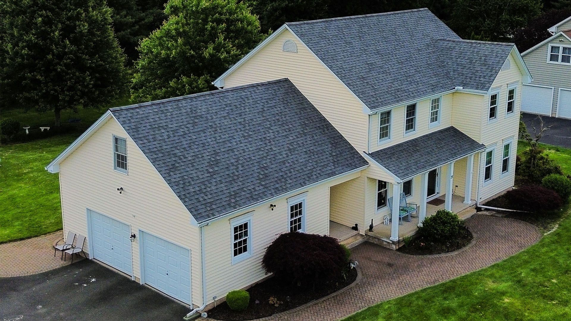 An aerial view of a large white house with a gray roof