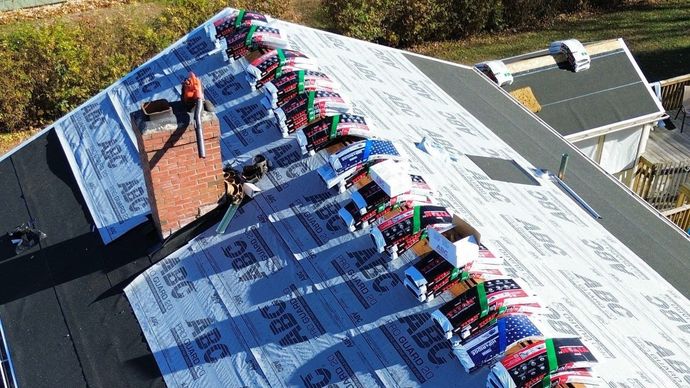A man is installing a gutter on the side of a house.