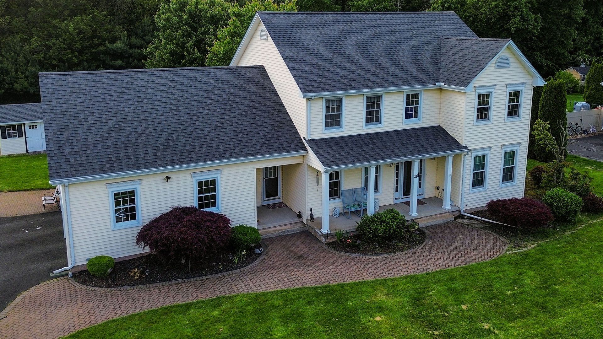 An aerial view of a large white house with a gray roof.