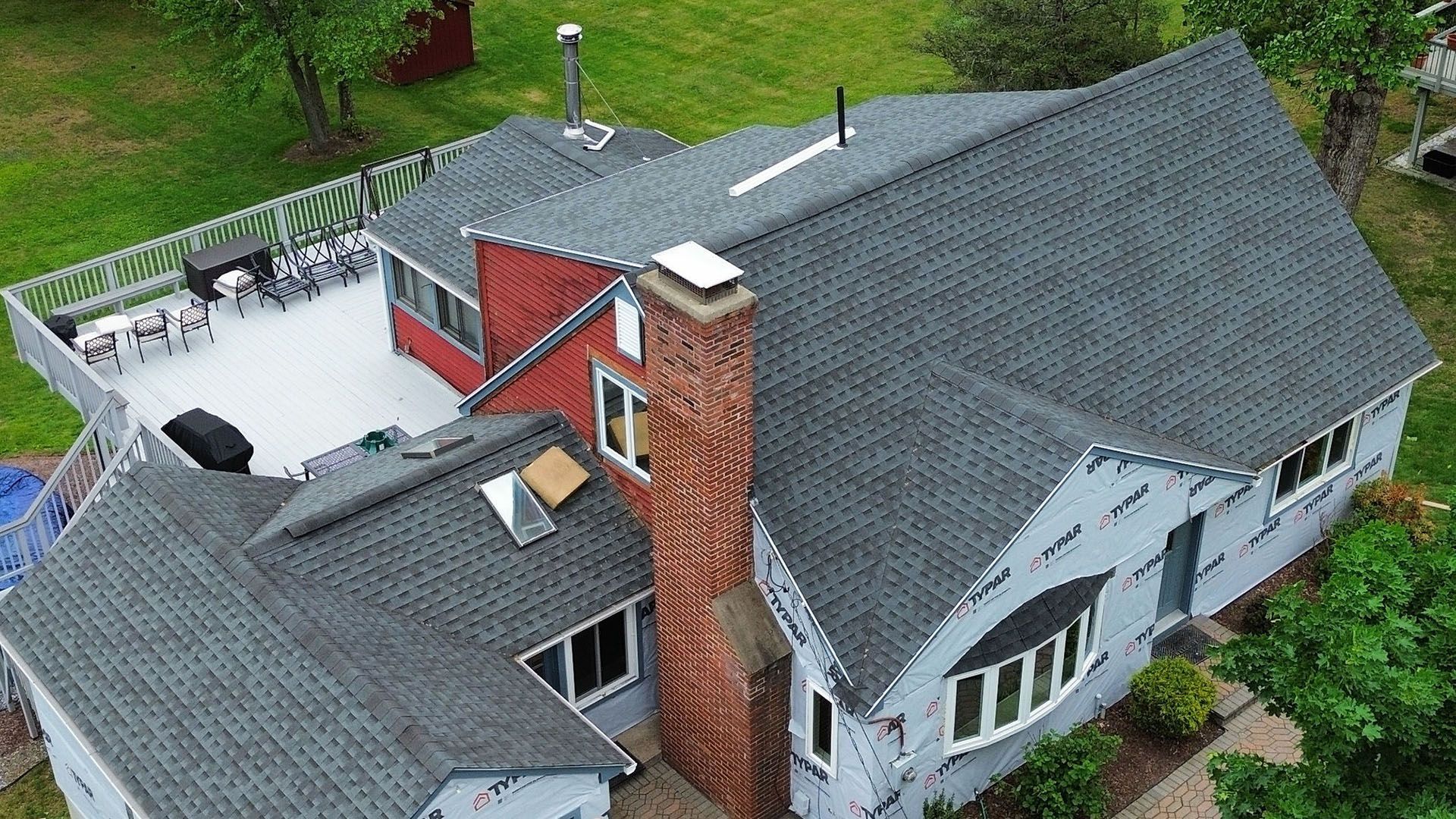 An aerial view of a house with a gray roof and a brick chimney.
