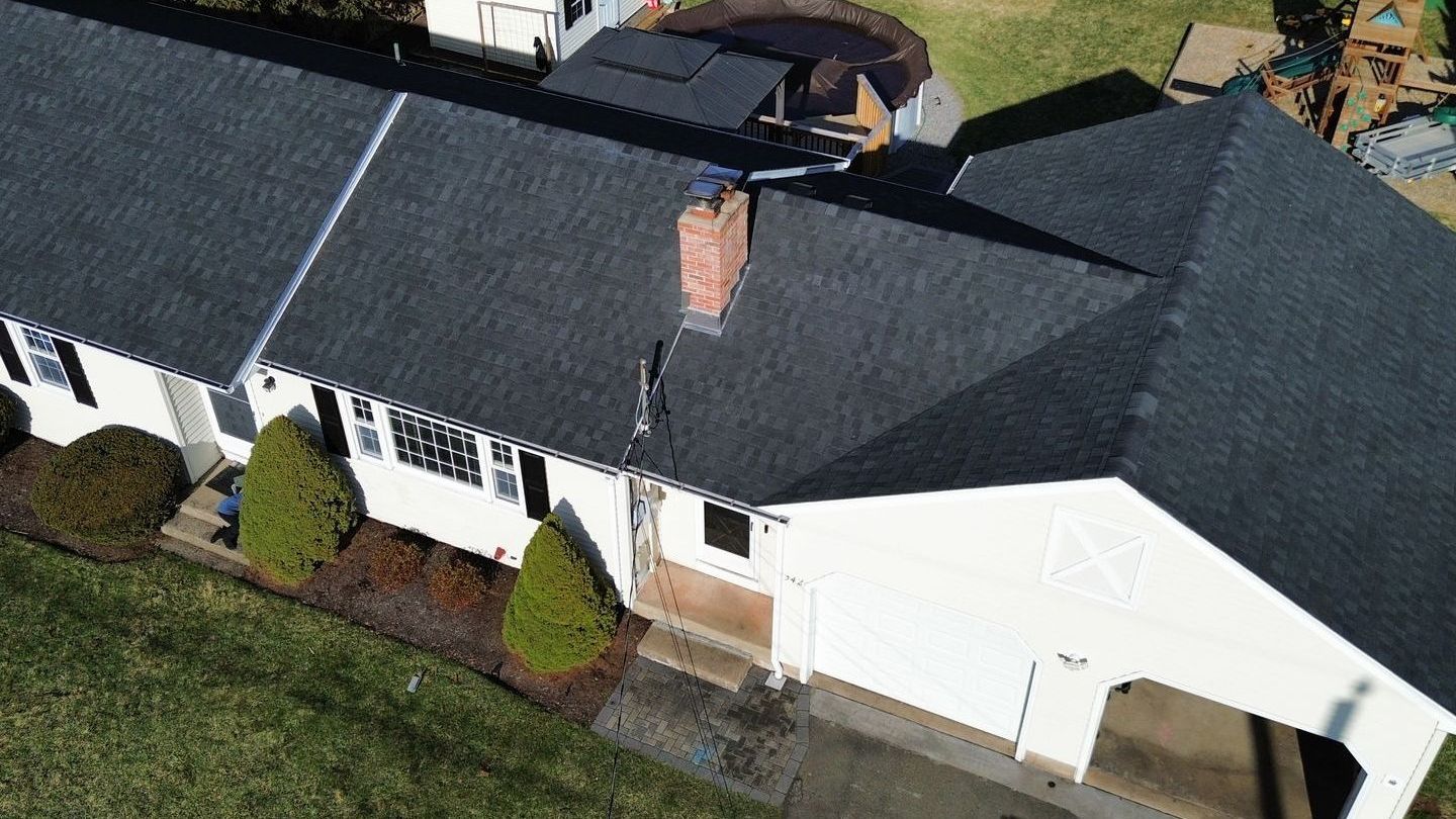 An aerial view of a large white house with a black roof.