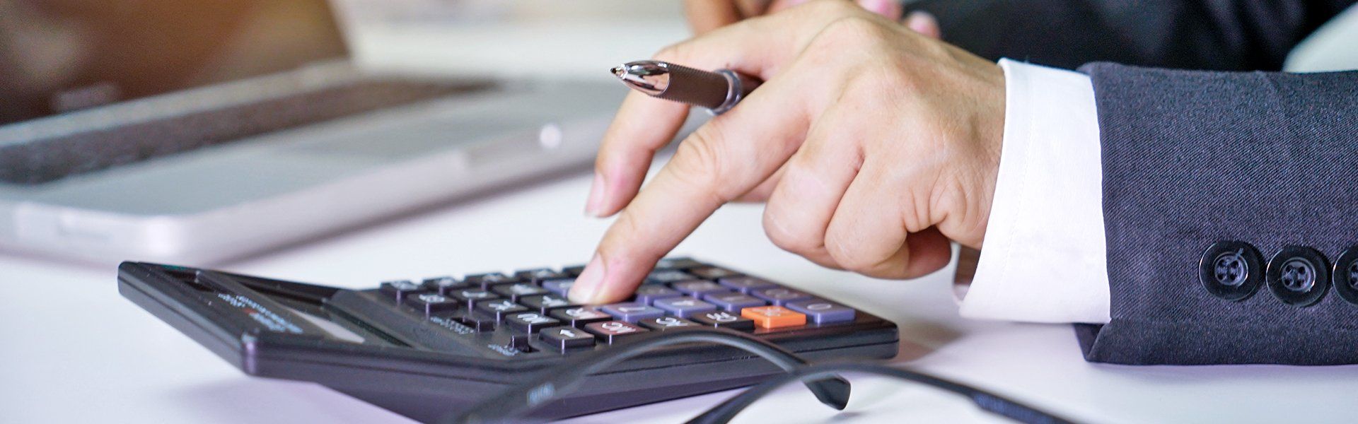 a person holding a pen and using a calculator
