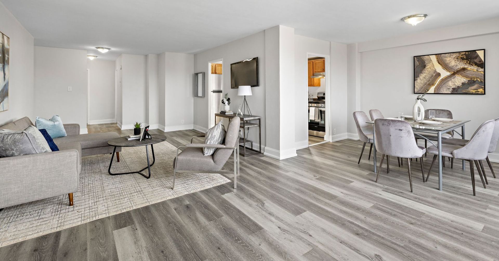 A living room and dining room in a large apartment with hardwood floors.