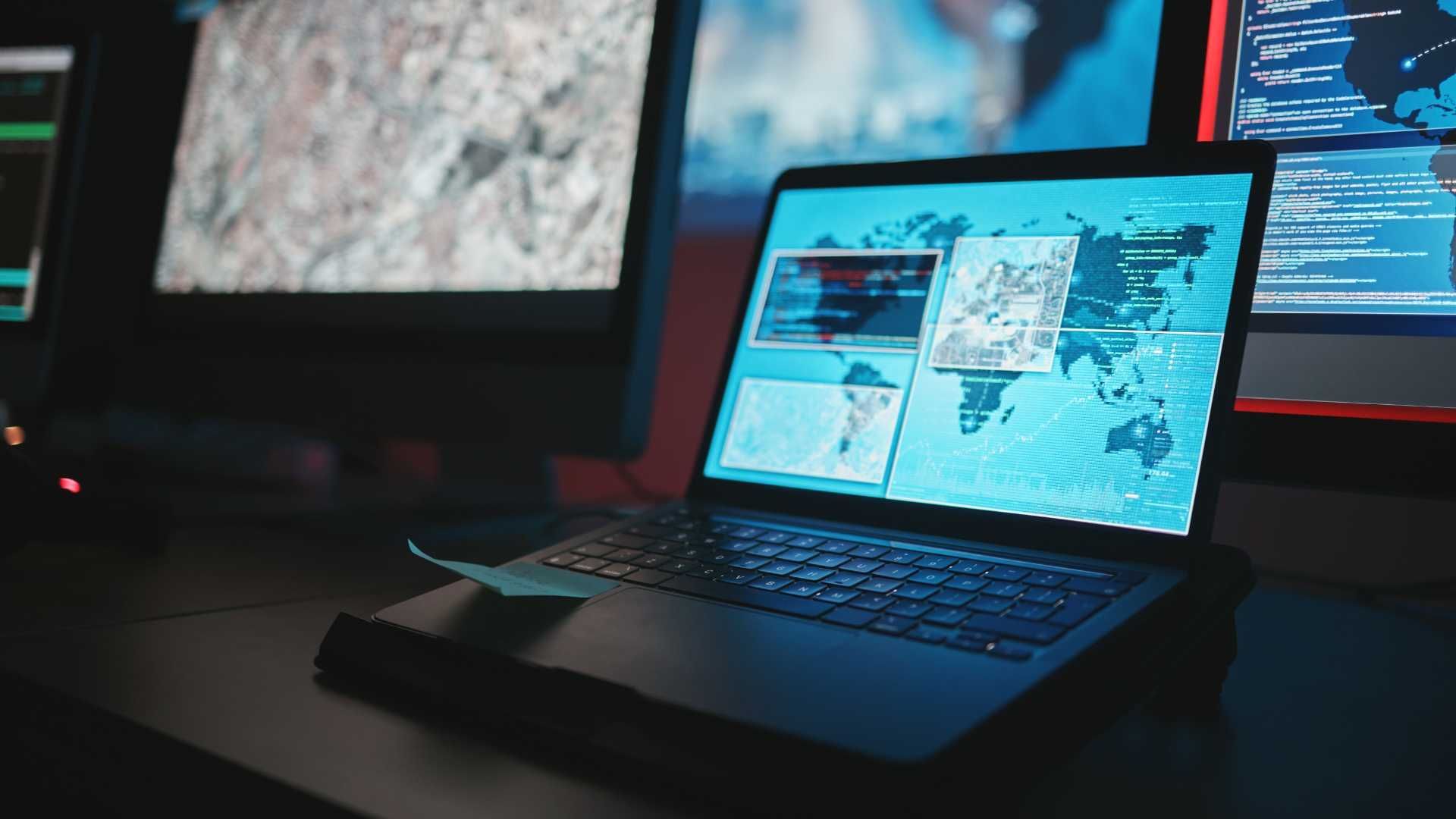 A laptop computer is sitting on a desk in front of a computer monitor.