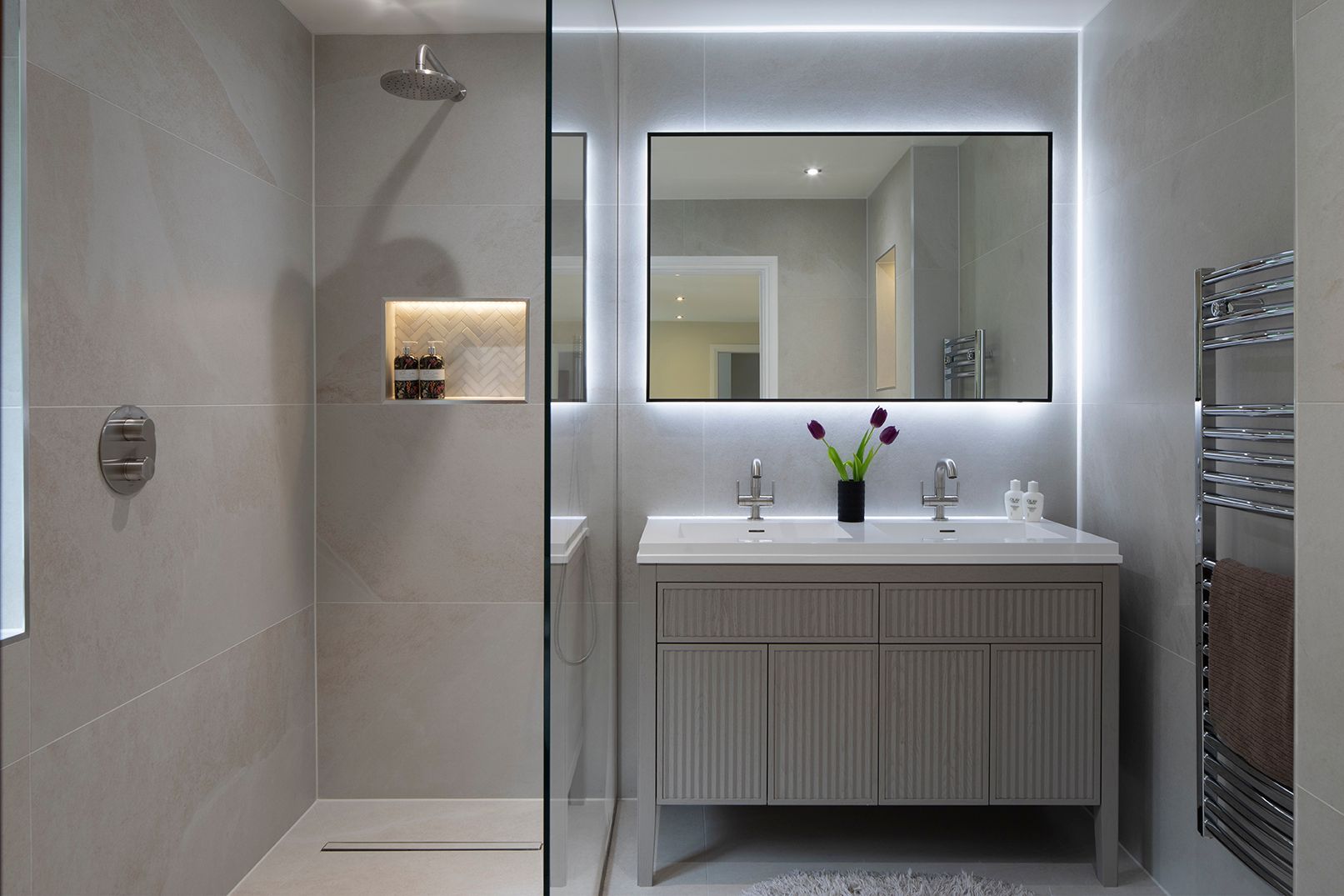 Walk-in shower with bespoke glass panel, herringbone niche, and chrome fixtures in Tewin by Elisa Design