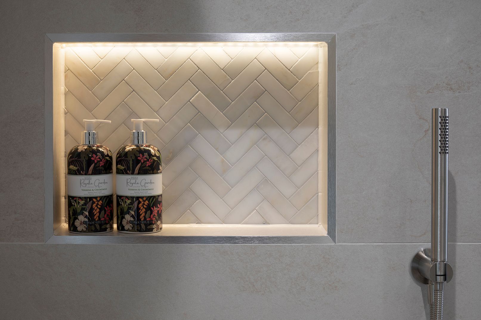 LED-lit herringbone marble niche with luxury toiletries in Tewin bathroom by Elisa Design