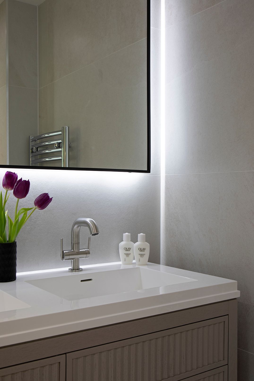 Contemporary bathroom with double vanity, reeded detailing, and black-framed mirror in Tewin