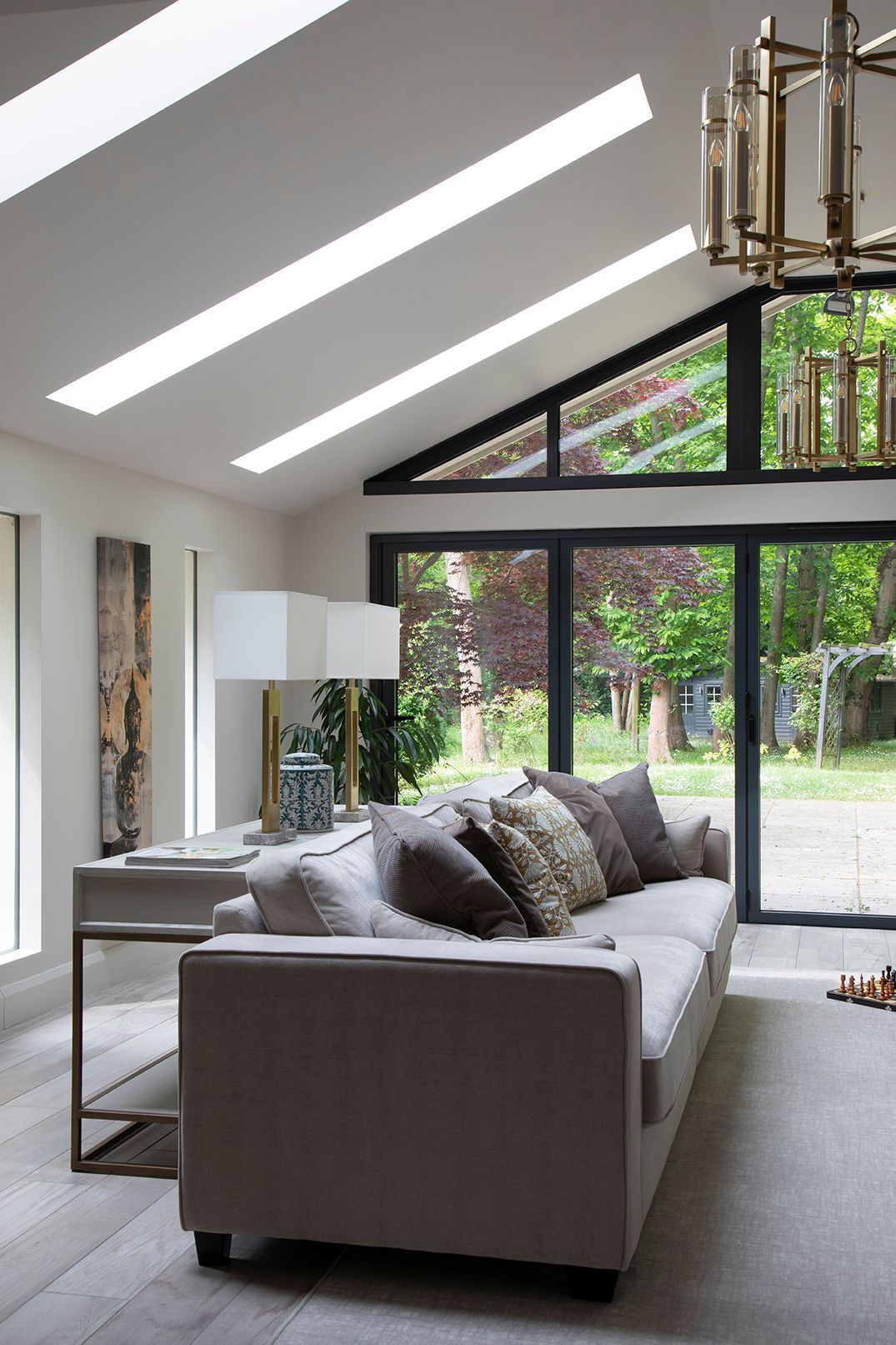Modern living room with grey velvet sofas, skylights, and garden views in Tewin by Elisa Design