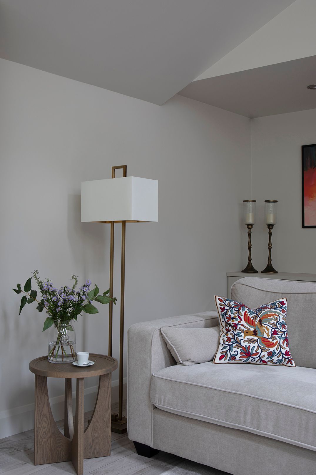 Grey velvet sofa with colourful patterned cushion and brass floor lamp in Tewin living room