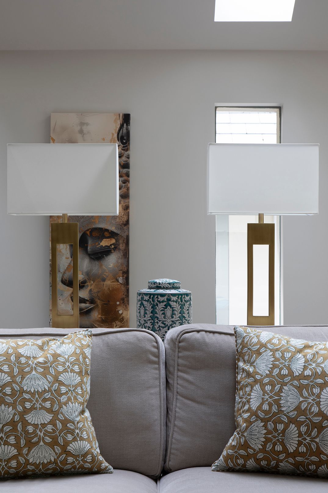 Console table with brass table lamps, abstract artwork, and blue-and-white ginger jar in Tewin by Elisa Design