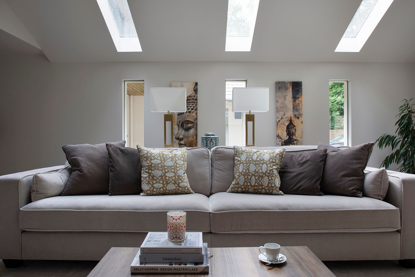 Grey velvet sofa with colourful patterned cushion and brass floor lamp in Tewin living room
