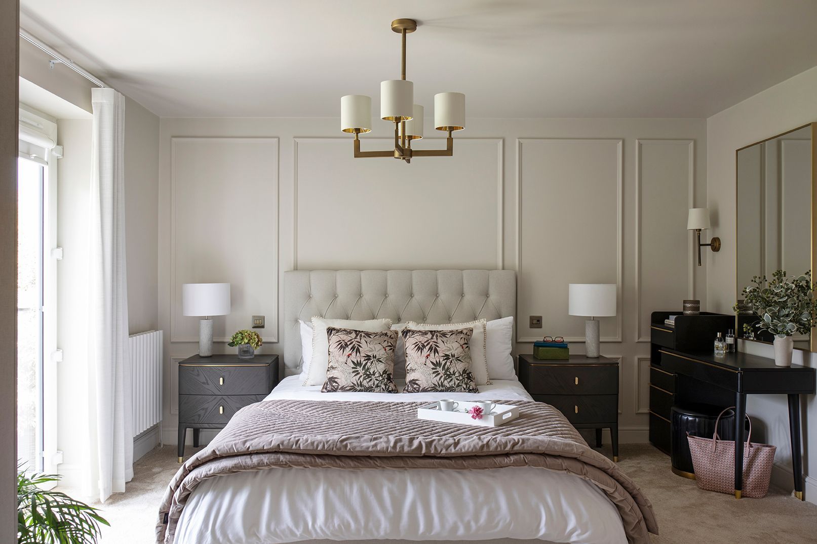 Luxury master bedroom with button-tufted headboard, wall panelling, and brass chandelier in Hertford by Elisa Design