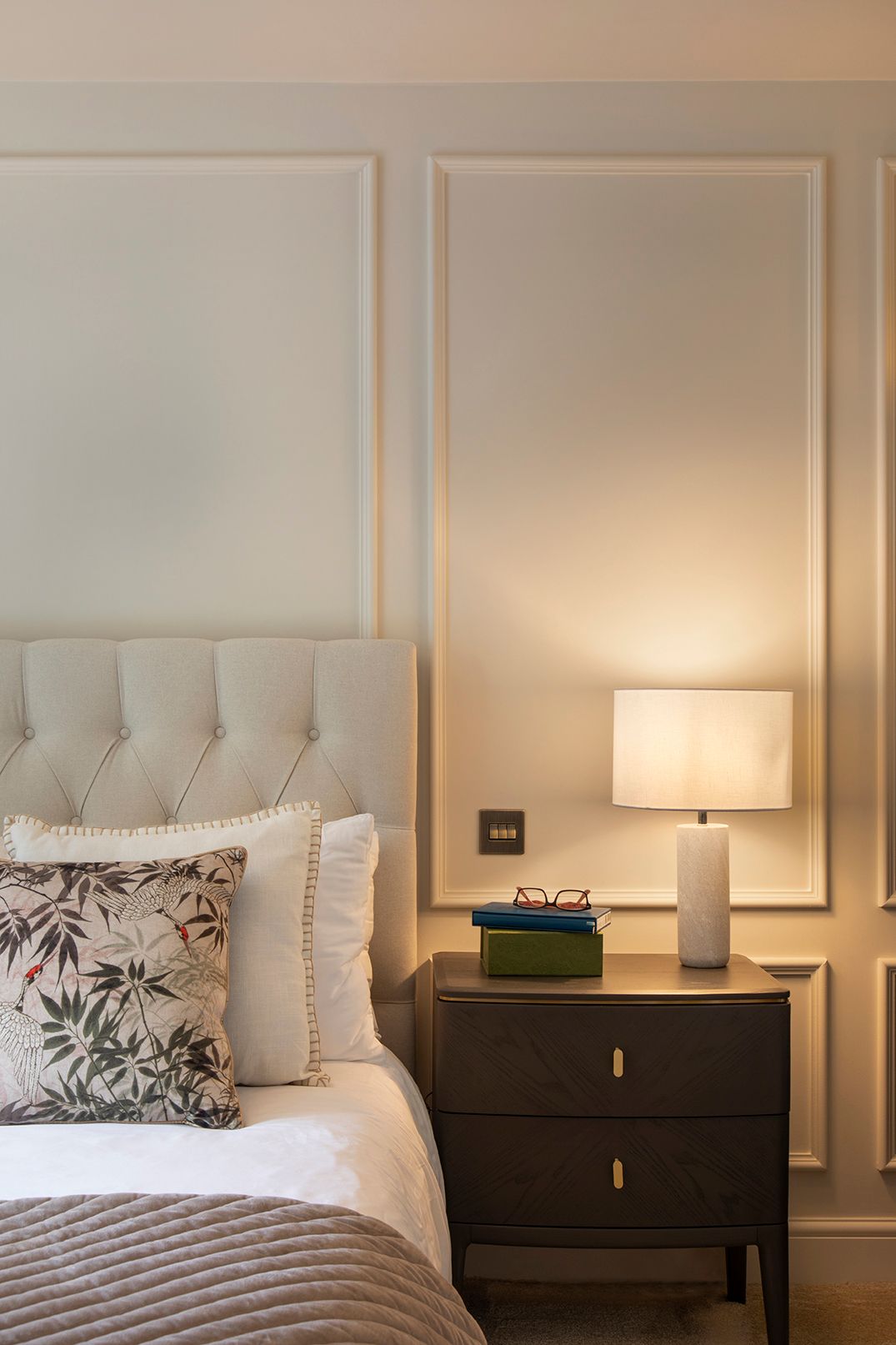 Bedside detail with black nightstand, brass lamp, and layered ambient lighting in Hertford master suite