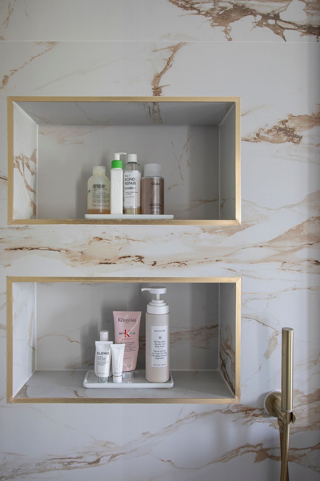 LED-lit shower niche with brass trim displaying luxury toiletries in Hertford marble ensuite