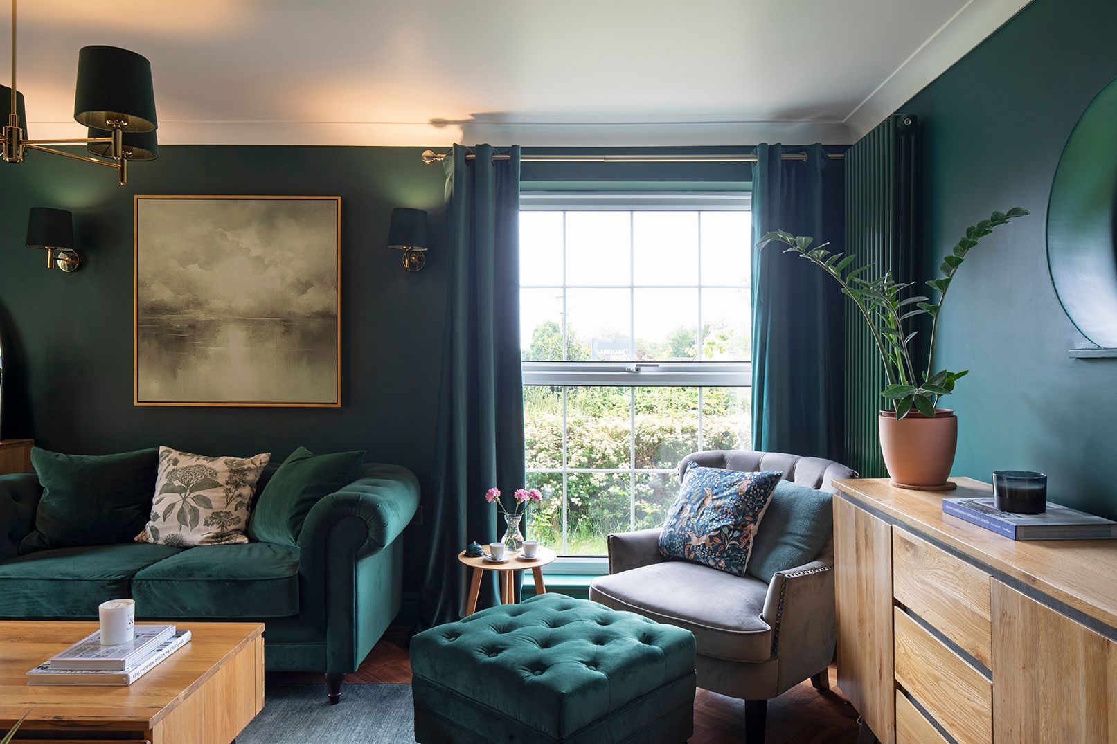 Hunter green living room with grey velvet accent chair, brass wall sconce, and abstract art - Elisa Design interior design