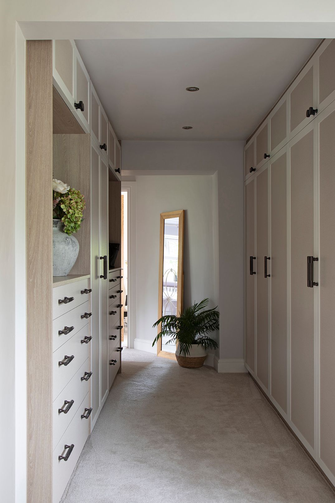 Floor-to-ceiling bespoke wardrobes with oak and painted panels, brass handles, in Welwyn Garden City home by Elisa Design