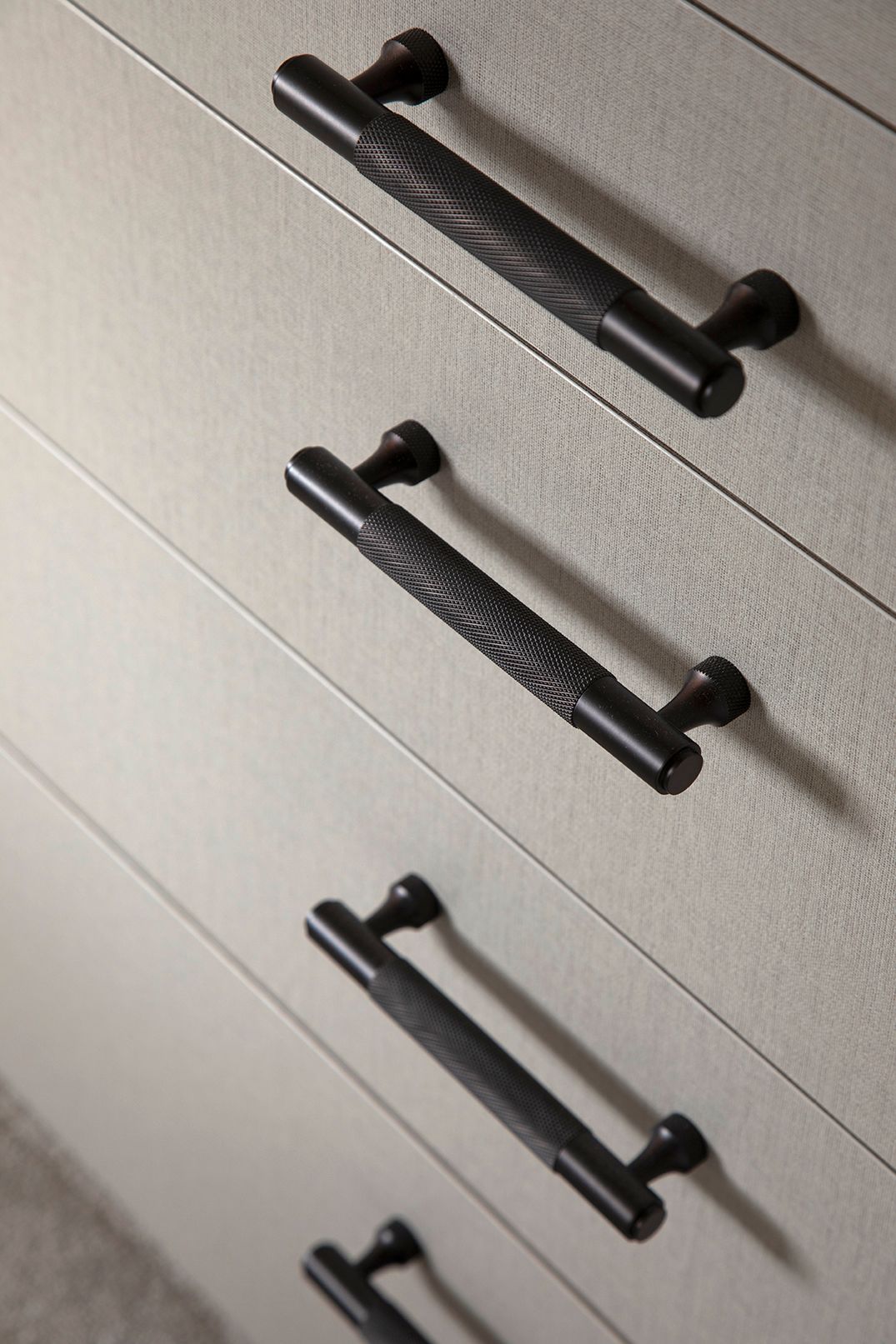 Close-up of Pushka Home brass knurled wardrobe handles in bronze on textured linen panels - Elisa Design bespoke joinery