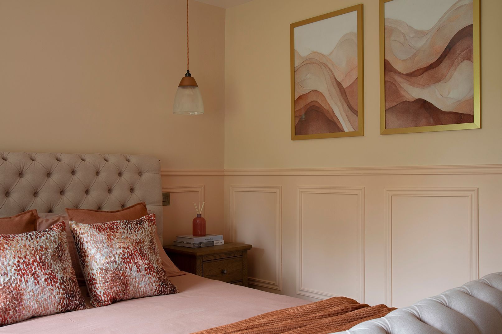 Master bedroom with tufted headboard, peach panelling, abstract art, and oak nightstand - Elisa Design interior design