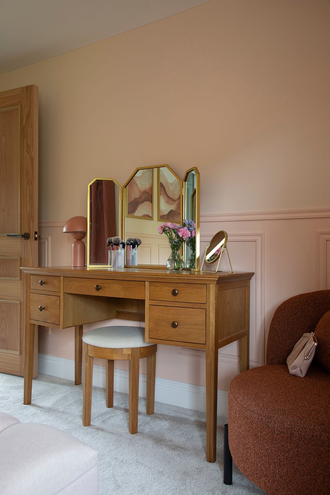 Oak dressing table with brass mirror and rust bouclé accent chair in master bedroom - Elisa Design Welwyn Garden City