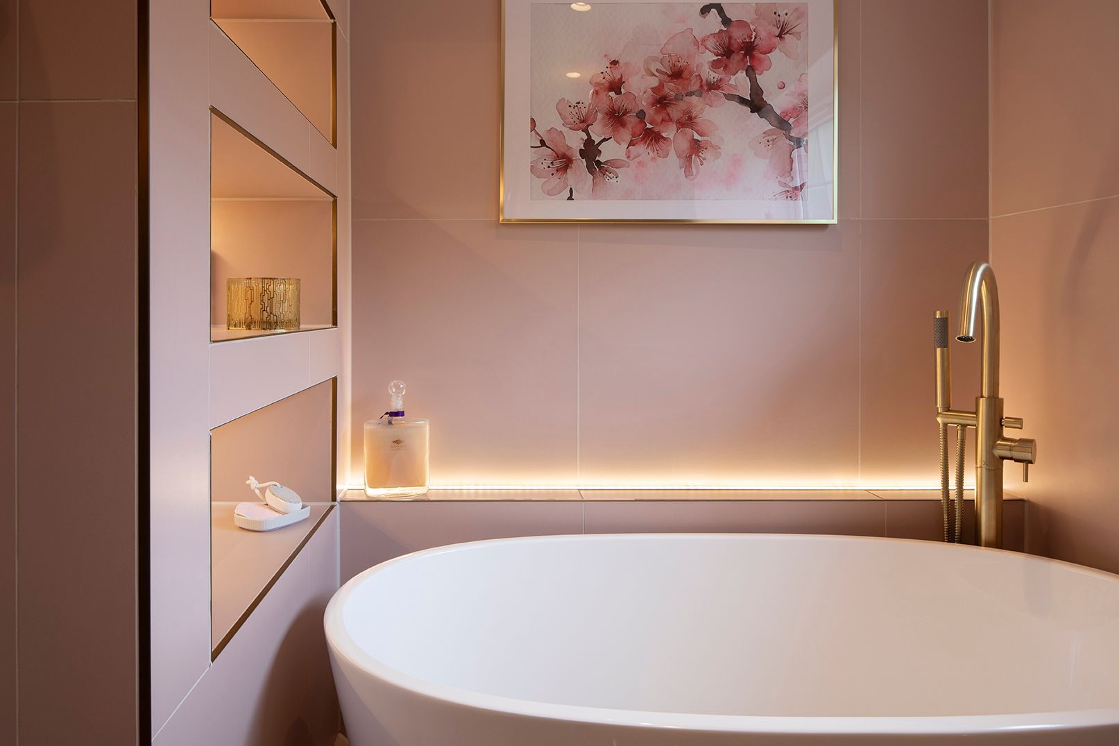 Freestanding bath with LED-lit wall niches, cherry blossom art, and brass floor-mounted filler - luxury bathroom design