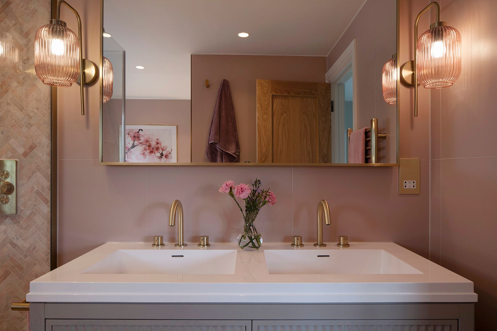 Double vanity with pink ribbed glass sconces, brass fixtures, and cherry blossom art - Elisa Design luxury bathroom