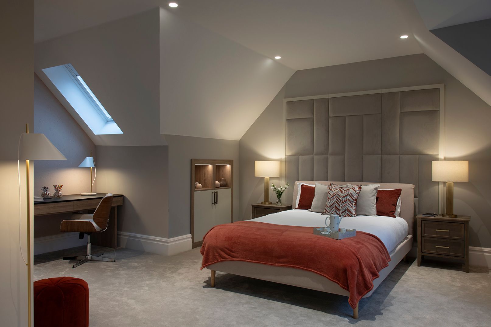 Loft conversion bedroom with taupe panelled headboard, brass lighting, and terracotta velvet accents in Bushey