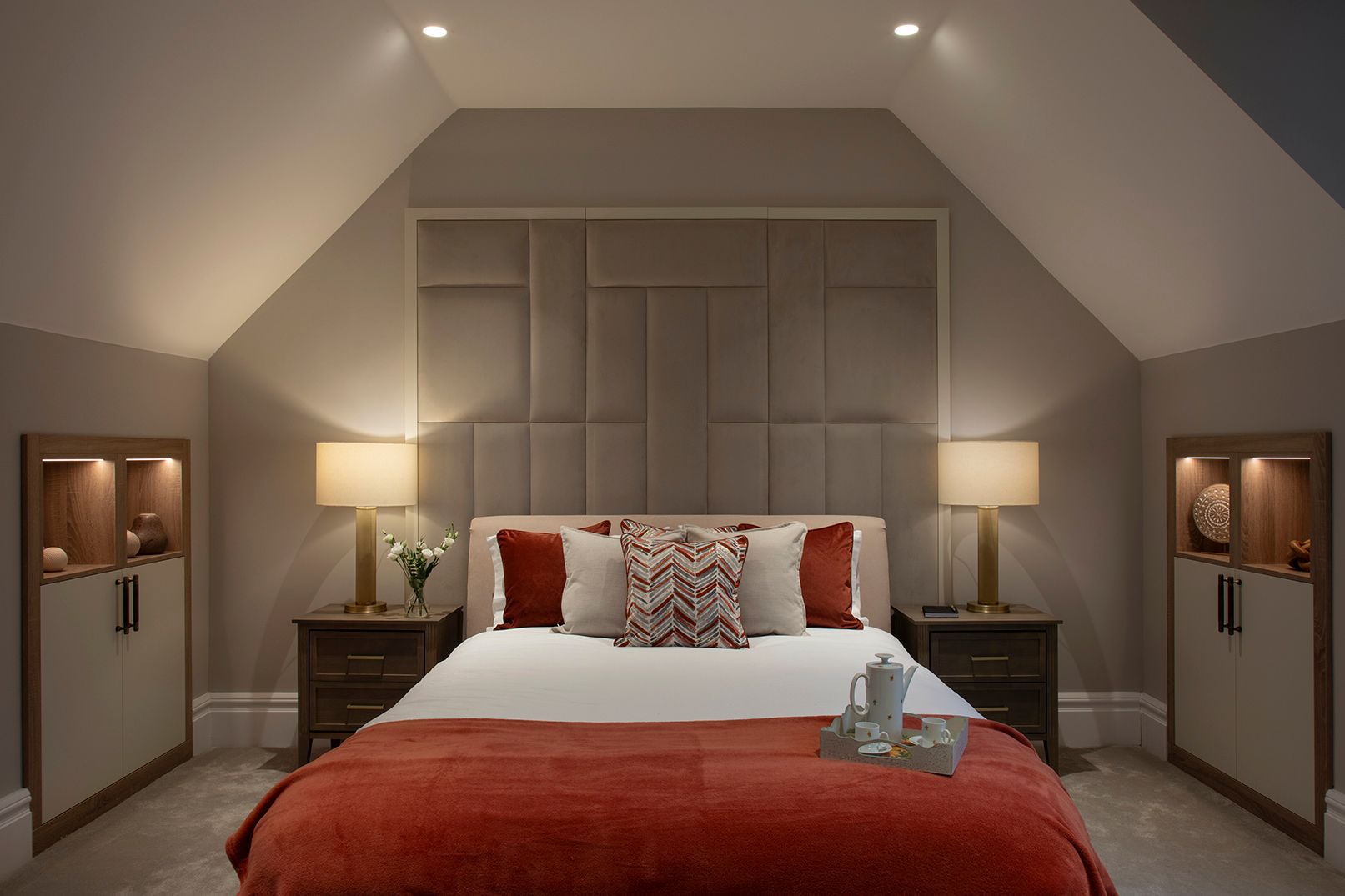 Luxury loft bedroom with bespoke taupe panelled headboard, vaulted ceilings, and warm ambient lighting in Bushey