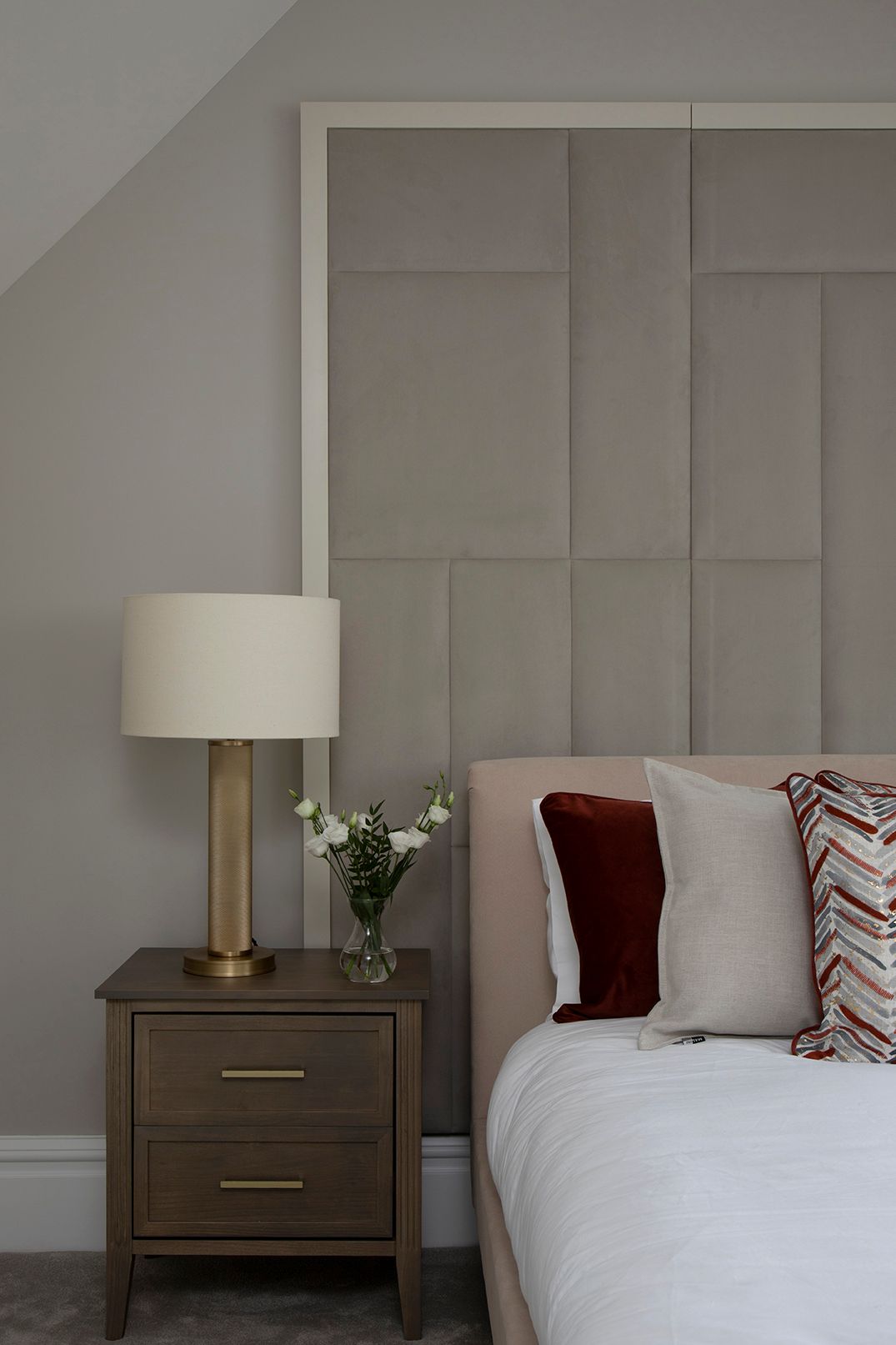 Elegant loft bedroom featuring geometric panelled headboard, brass table lamps, and terracotta velvet bedding in Bushey