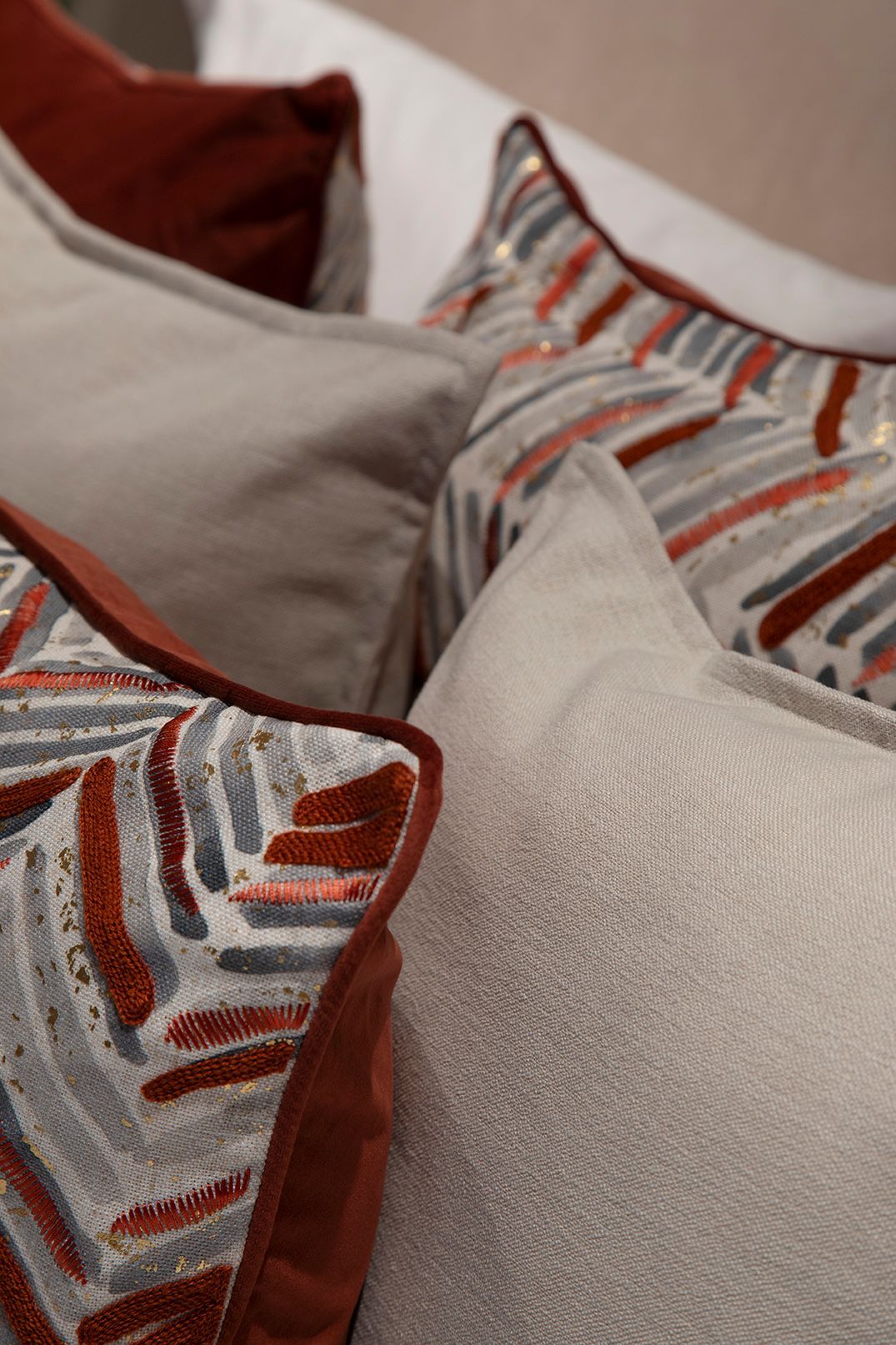 Close-up of layered cushions in terracotta velvet and chevron pattern on luxury loft bed in Bushey