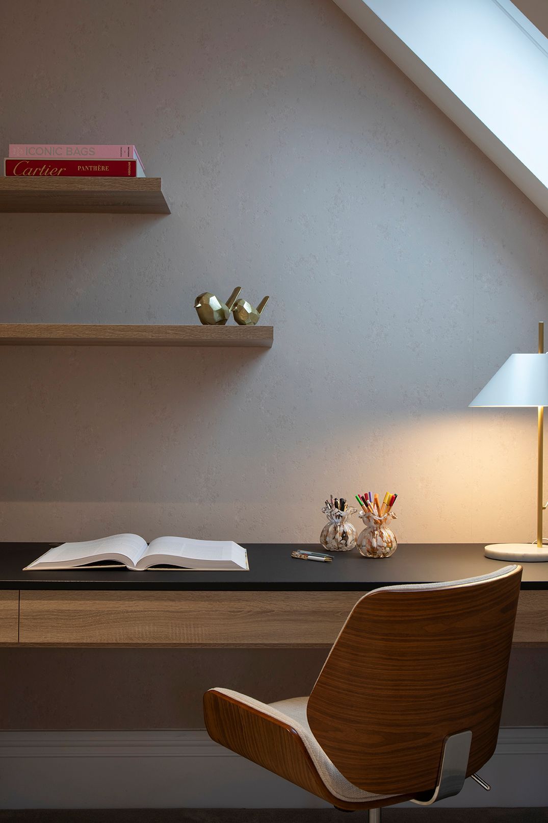 Under-eaves workspace with bespoke oak shelving and integrated storage in Bushey loft home office by Elisa Design