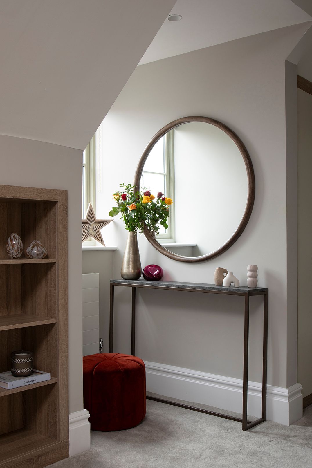 Loft landing with round walnut mirror, console table, and terracotta velvet pouf in Bushey loft suite by Elisa Design