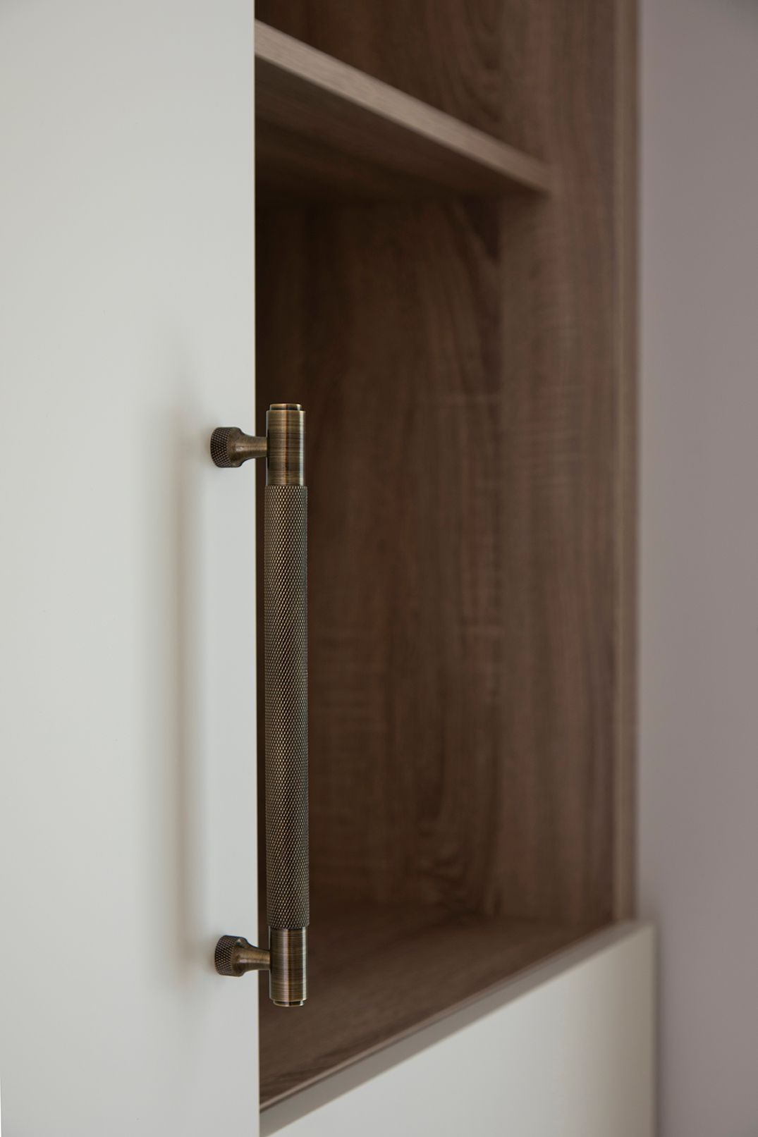 Knurled brass wardrobe handle detail on bespoke joinery in Bushey loft suite by Elisa Design