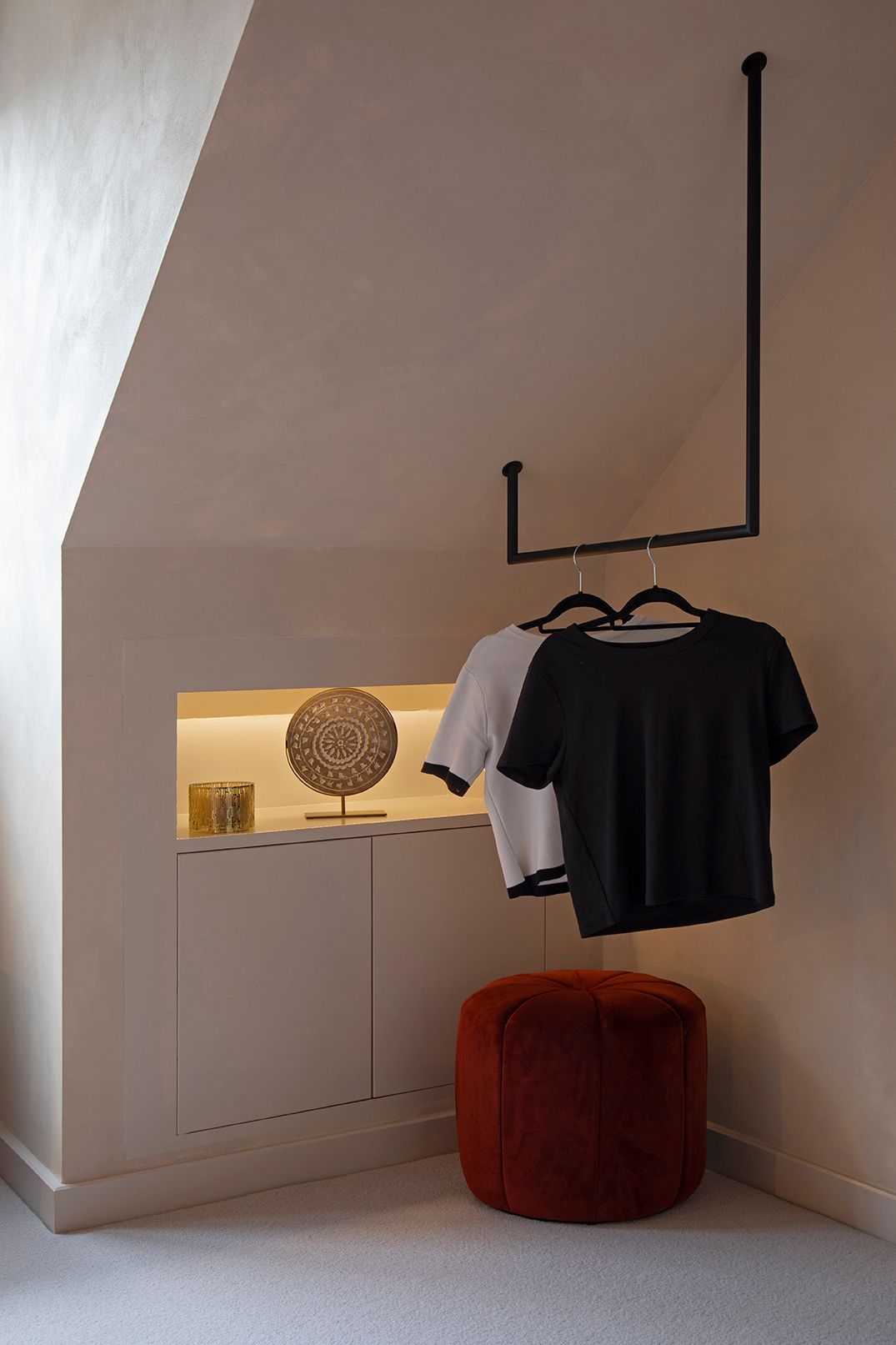 Open hanging rail integrated into sloped-ceiling storage, highlighting bespoke carpentry and minimal styling in Watford.