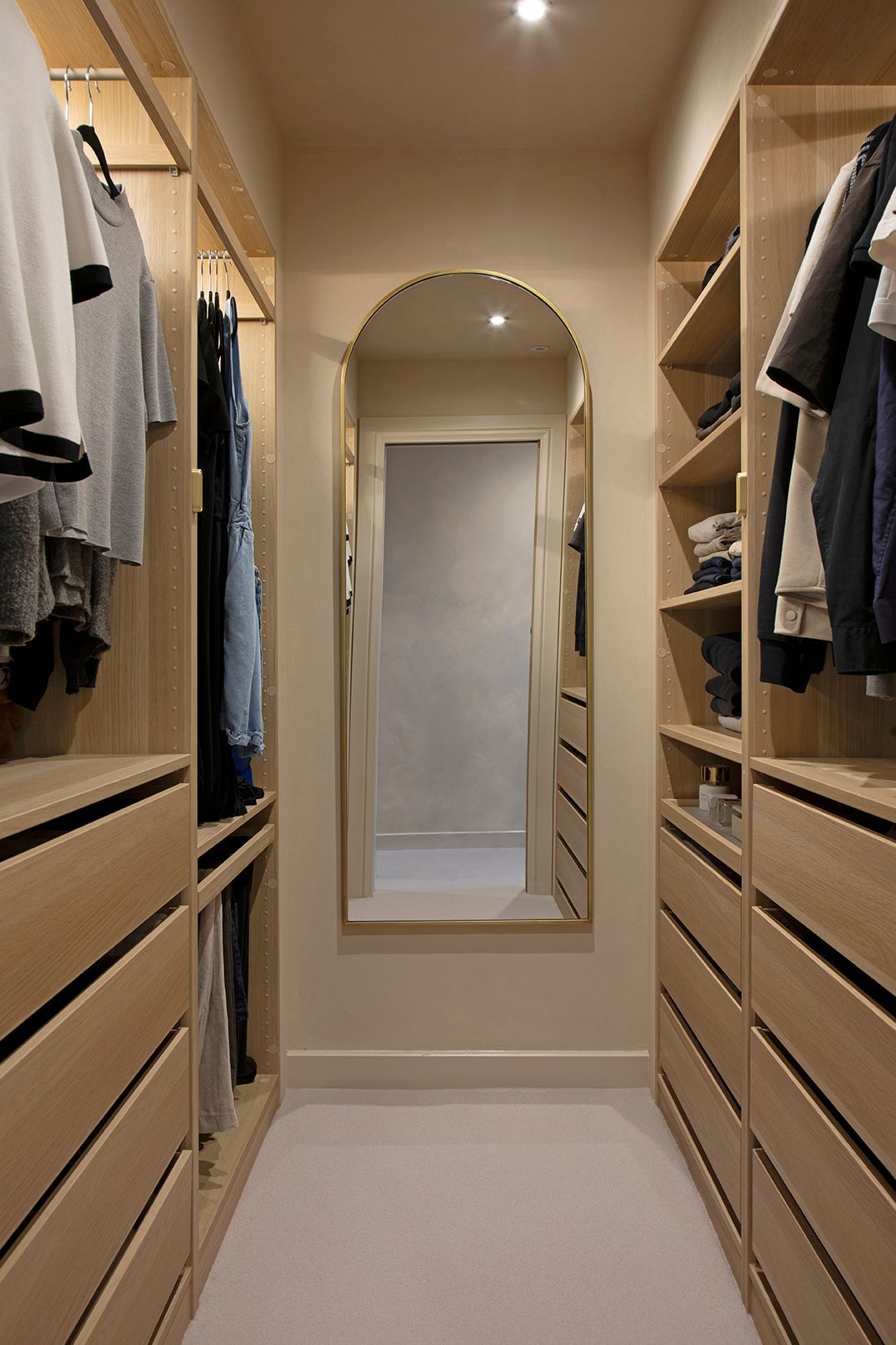 Bespoke oak walk-in wardrobe with brass mirror and limewash walls in Watford loft suite