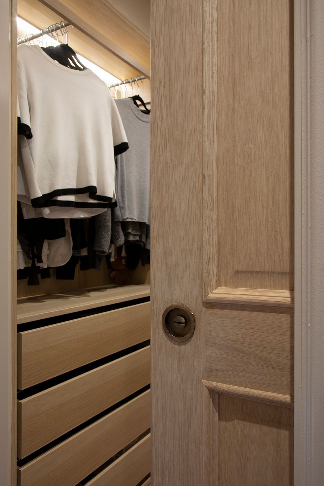 A section of oak joinery with neatly folded clothes and rails for hanging garments.