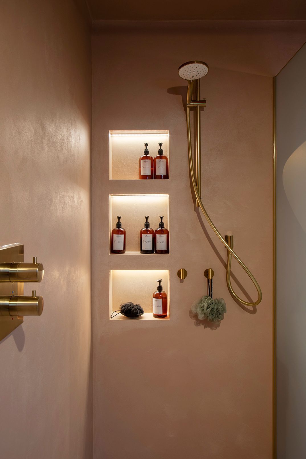 Luxury shower with LED-lit niches, brass fixtures, and warm microcement finish in Watford ensuite