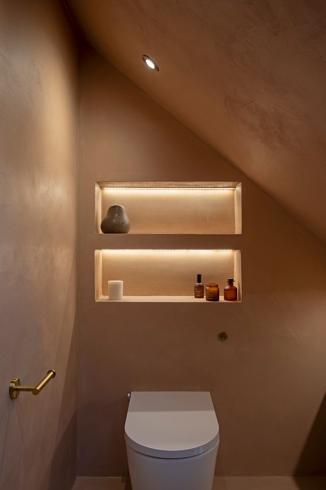 Modern bathroom shelving with integrated LED lighting and soft blush plaster finish — a bespoke interior by Elisa Design