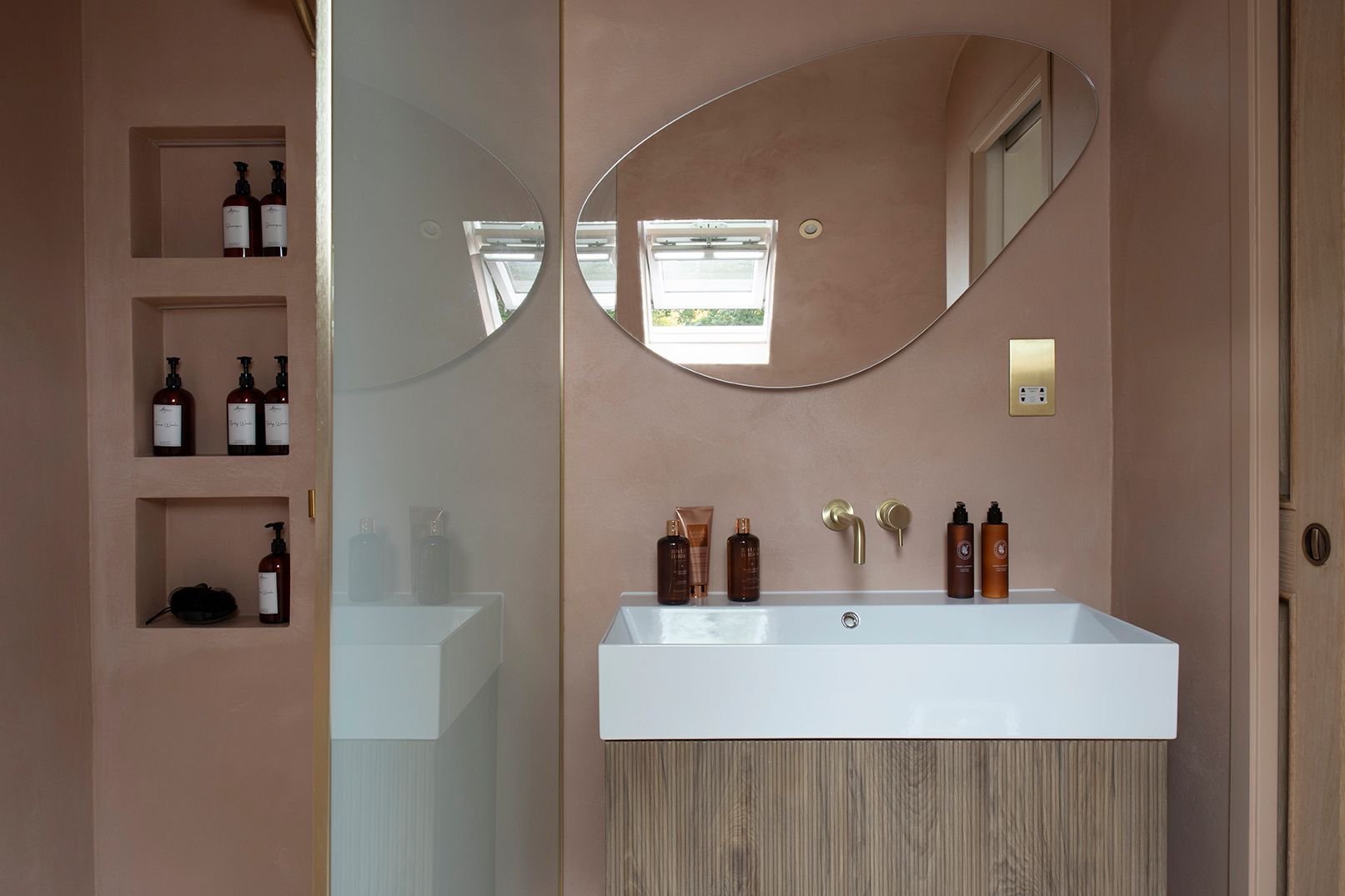Complete ensuite view showing microcement walls, LED-lit niches, curved mirror, and oak vanity in Watford loft
