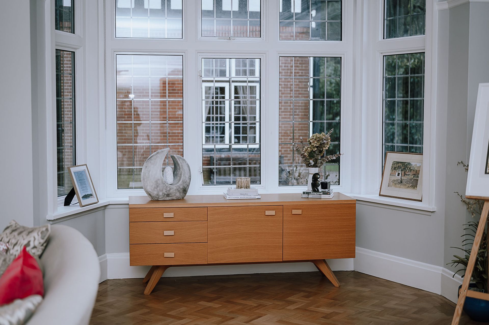 Bay window with mid‑century style sideboard, styled accessories and views to the school grounds.