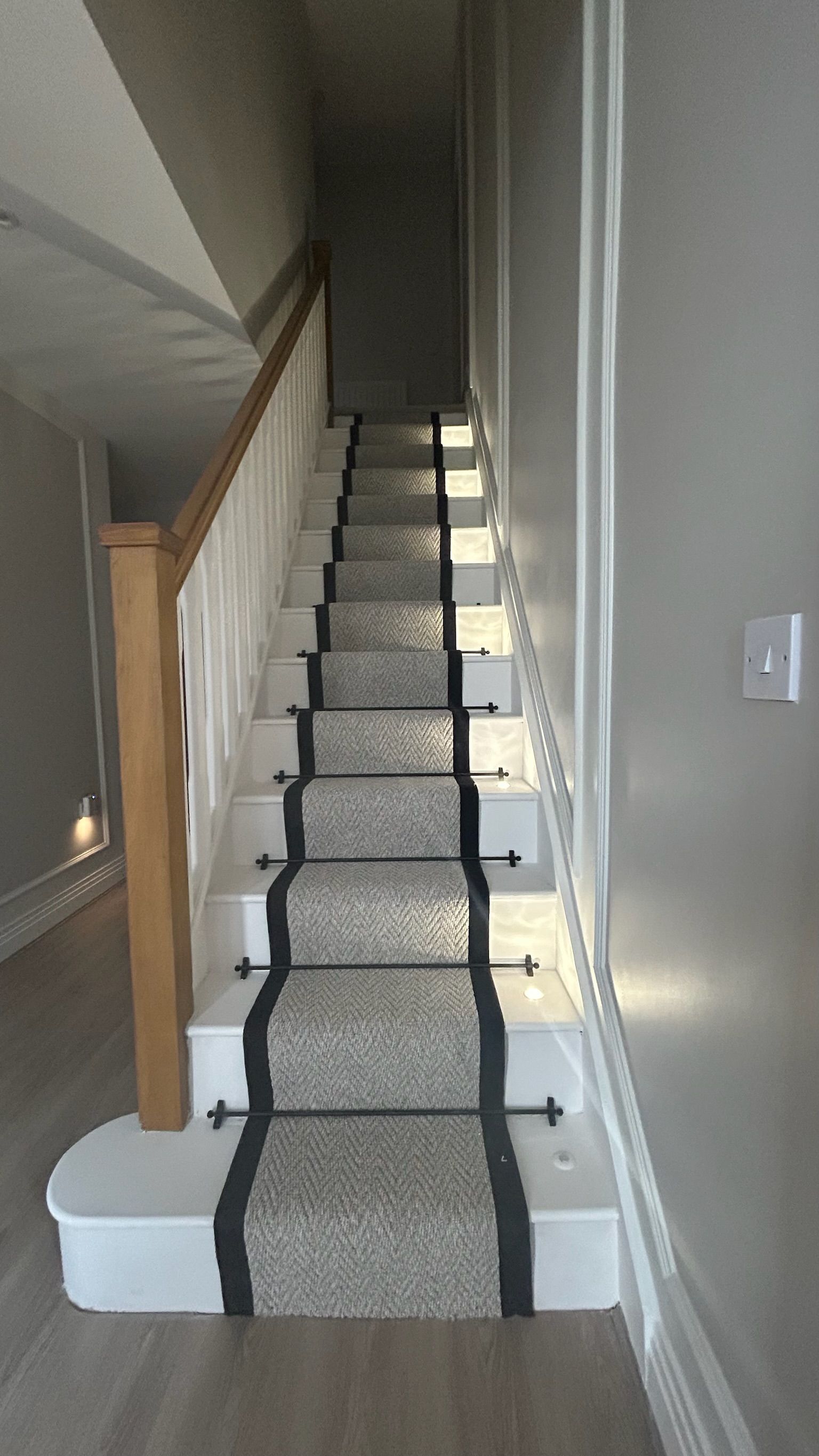 Full hallway view showcasing staircase, contemporary wall treatment, and layered lighting design.