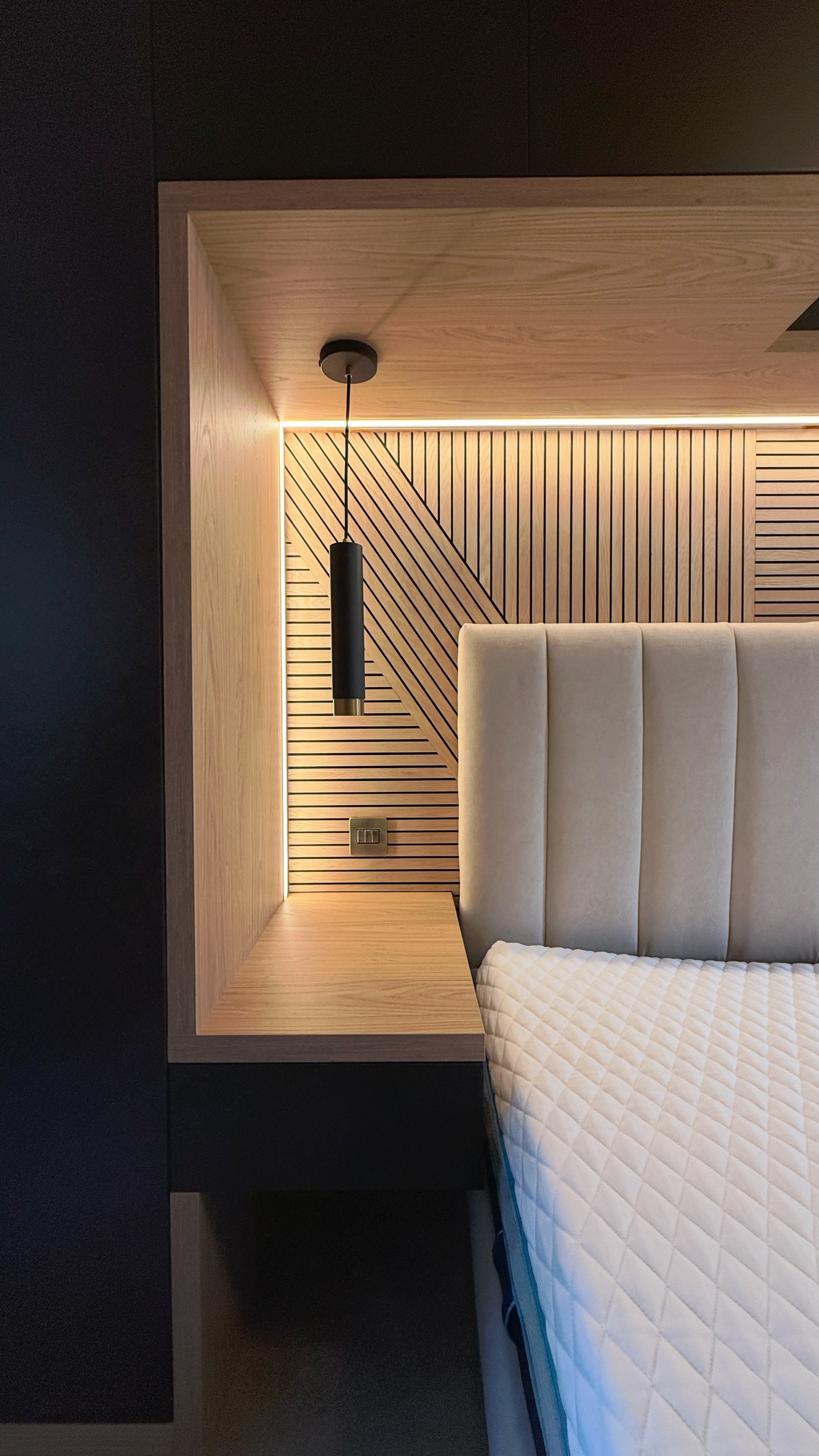 Timber bed niche with slatted headboard, black pendant light and warm LED strip in The Welwyn Family Edit.